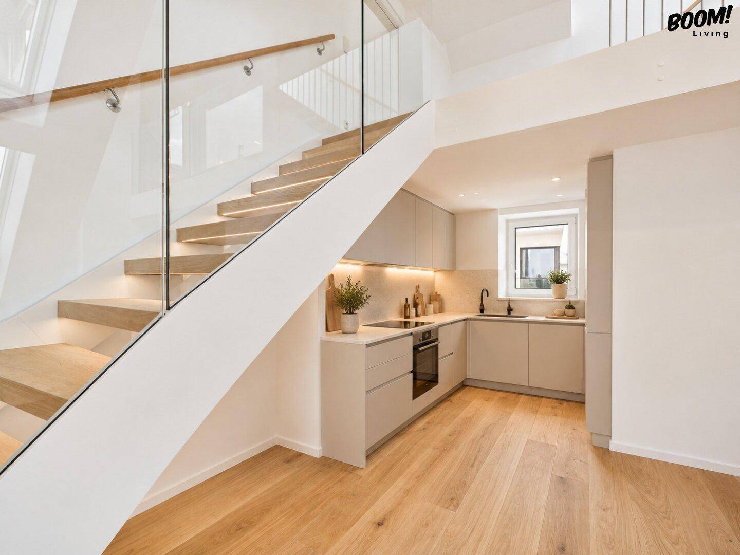Moderne Einbauküche unter der Treppe mit hellen Schränken, Holzfußboden und integrierten Geräten.