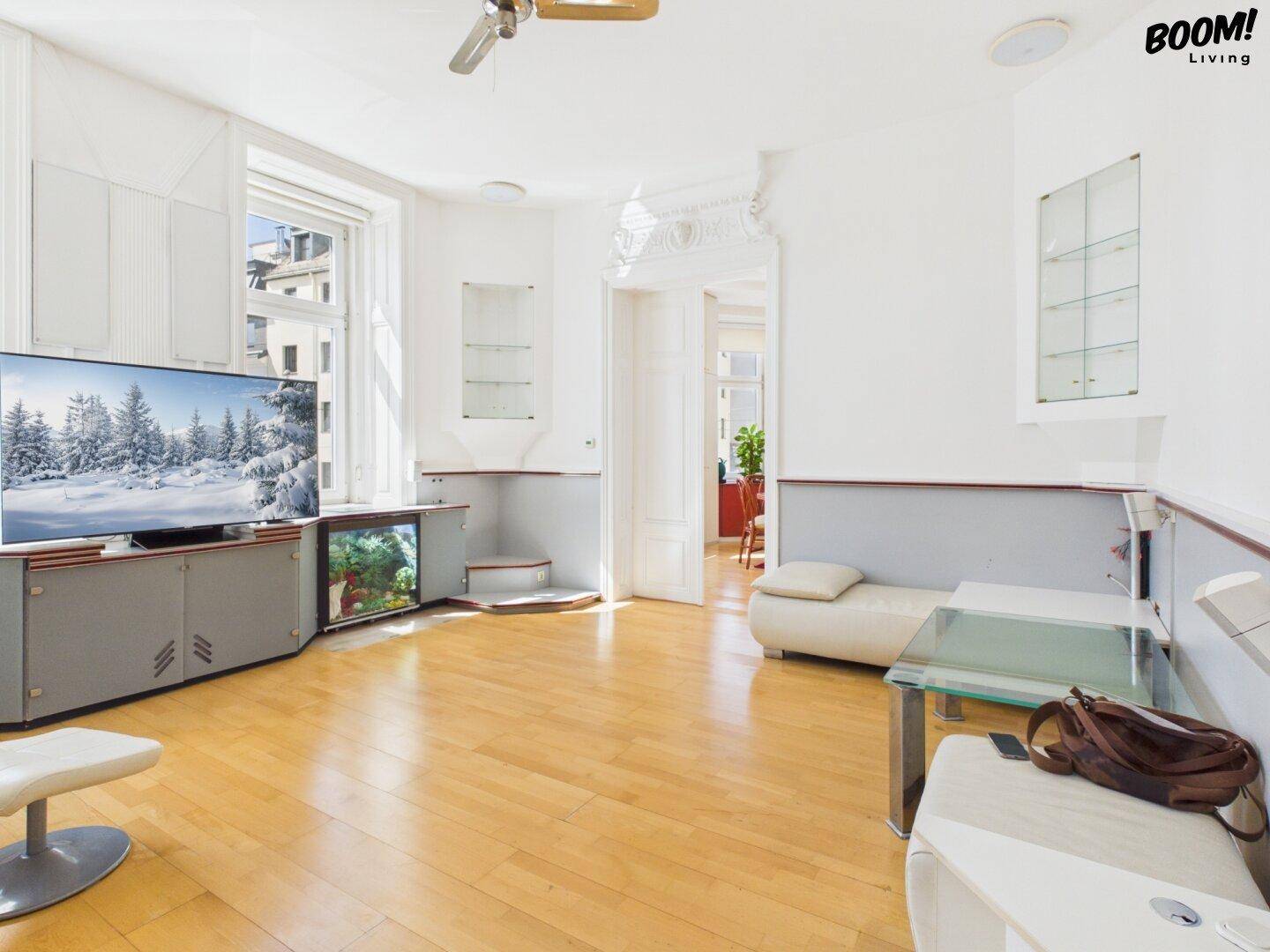 Geräumiges Wohnzimmer mit Parkettboden, TV-Möbeln und Blick auf die Stadt.