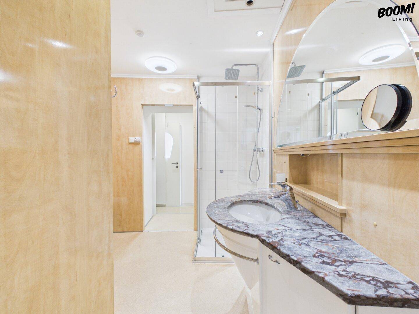 Badezimmer mit Marmorwaschtisch, Duschkabine und Holzverkleidung an den Wänden.