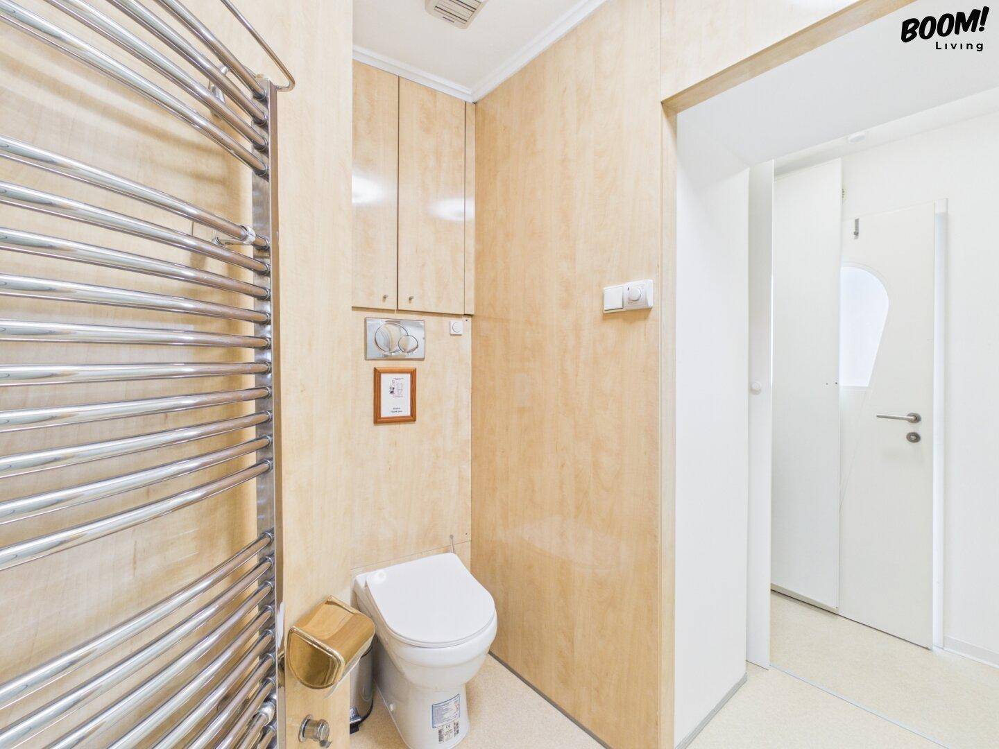 Separate Toilette mit Wand-WC, Handtuchheizkörper und Holzverkleidung.