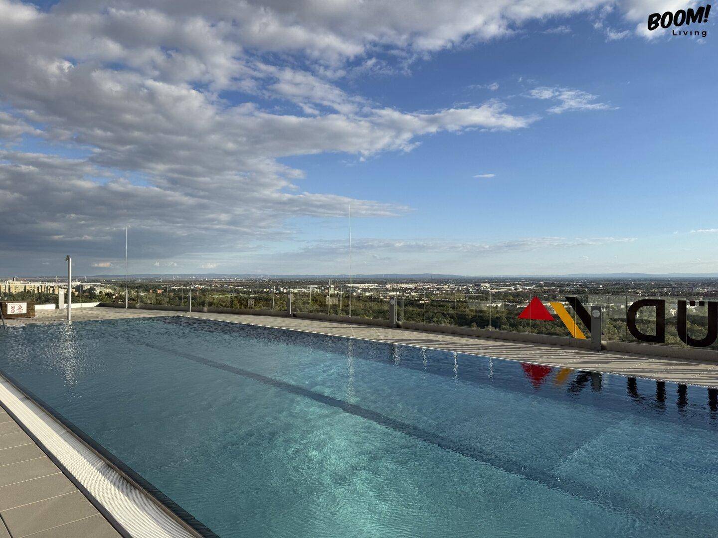 Beeindruckender Infinity-Pool auf dem Dach mit weitem Blick über die Stadt und die Landschaft.