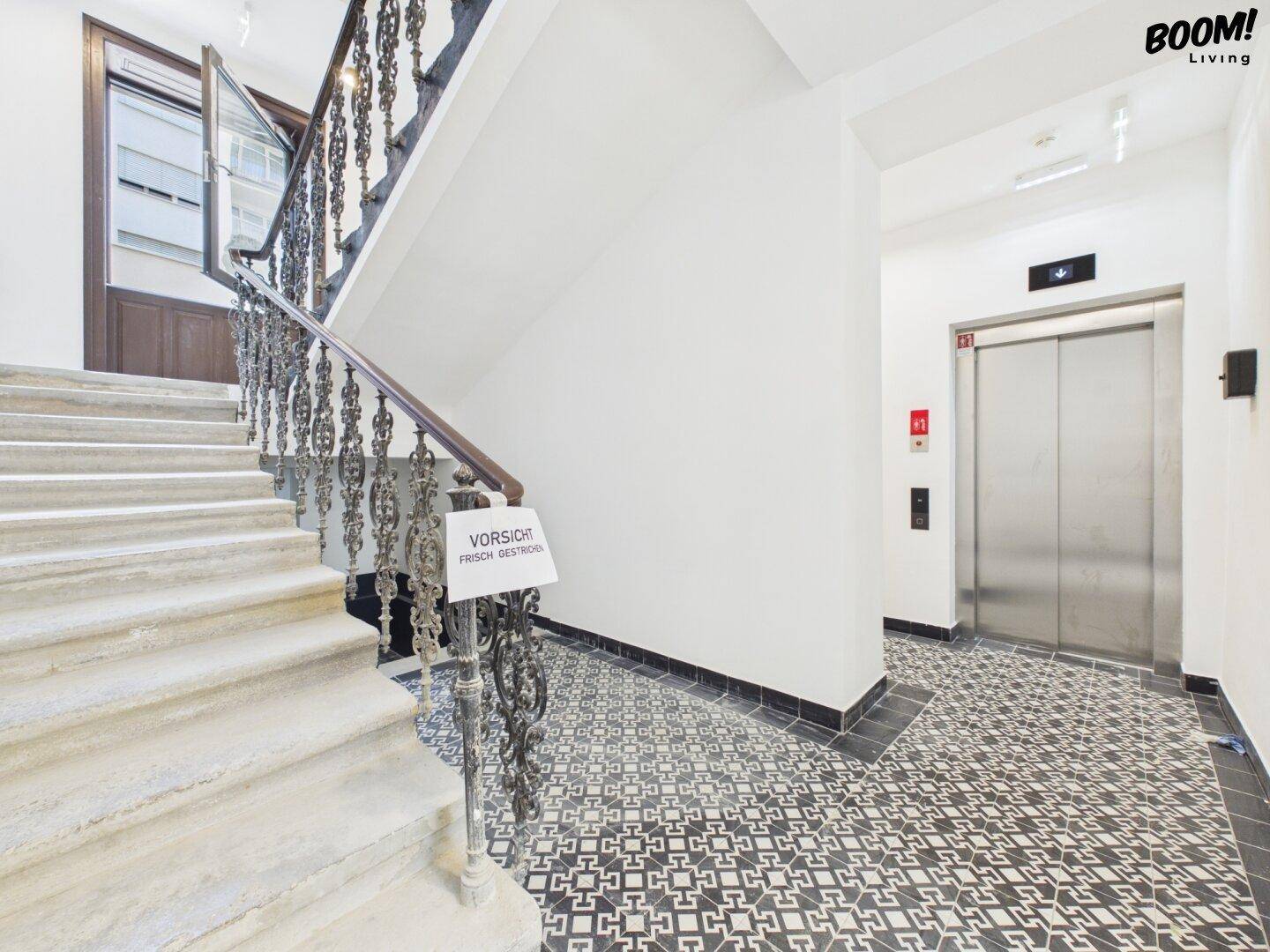 Treppenhaus mit elegantem Geländer und modernem Aufzug in einem gepflegten Gebäude.