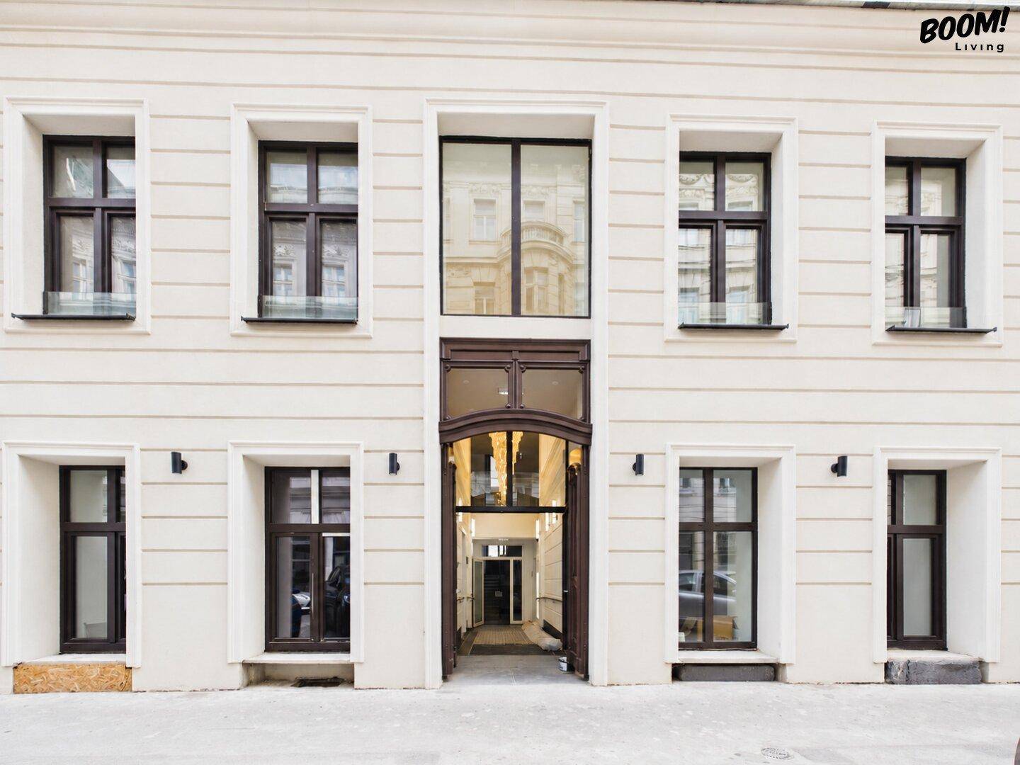 Klassische Fassade eines Wohngebäudes mit großen Fenstern und einem einladenden Eingangsbereich.