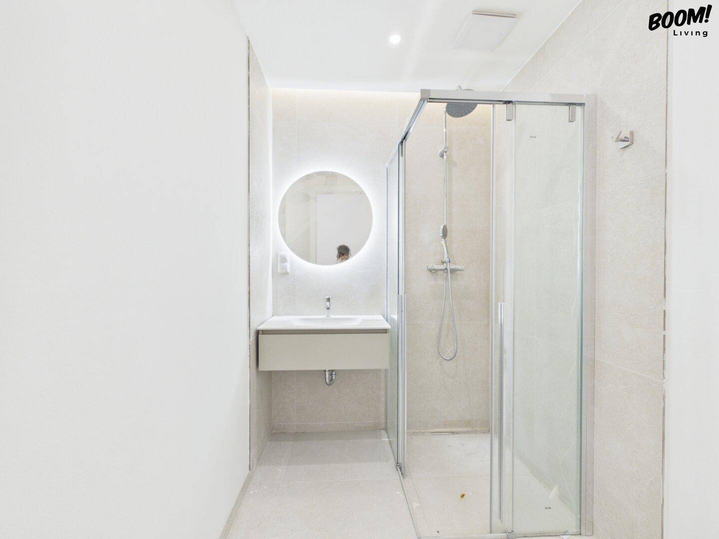 Modernes Badezimmer mit begehbarer Dusche, beleuchtetem Spiegel und minimalistischem Design.