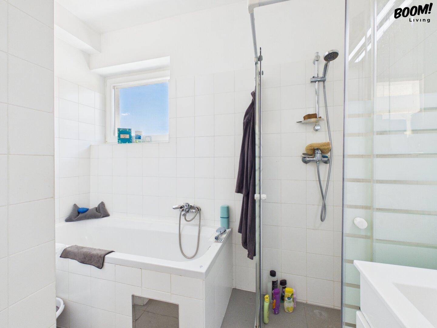 Modernes Badezimmer mit Badewanne, Duschkabine und Fenster für Tageslicht.