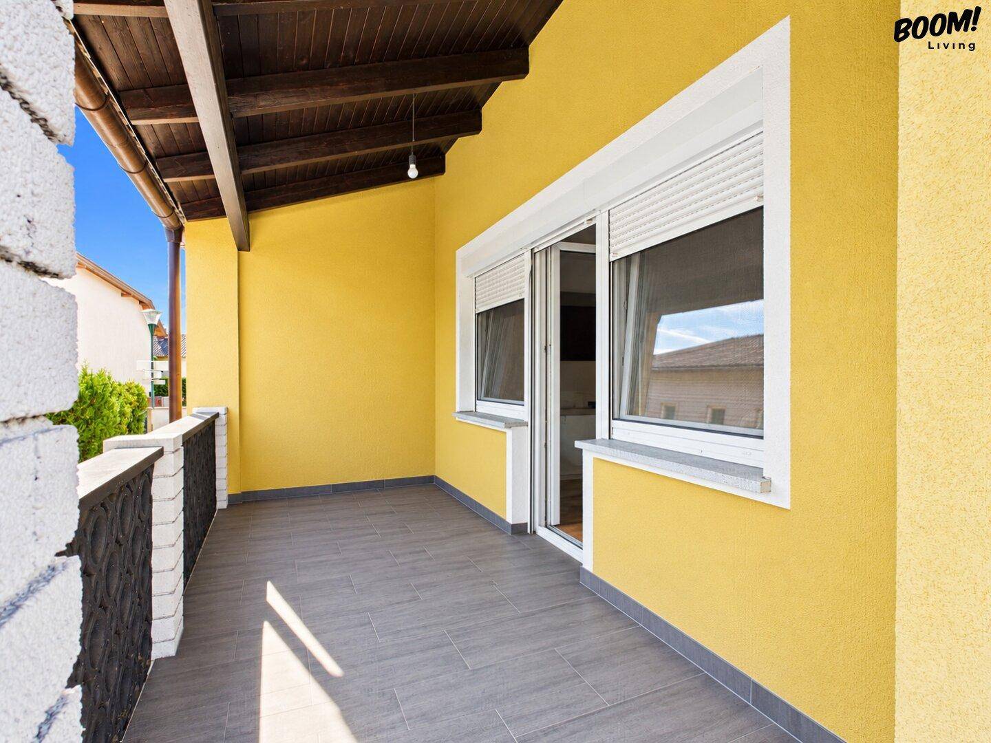 Überdachter Balkon mit Fliesenboden und Blick auf die Umgebung.