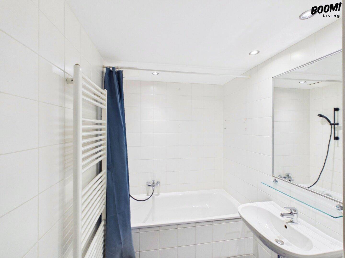 Helles Badezimmer mit Badewanne, Waschbecken und weißen Fliesen.