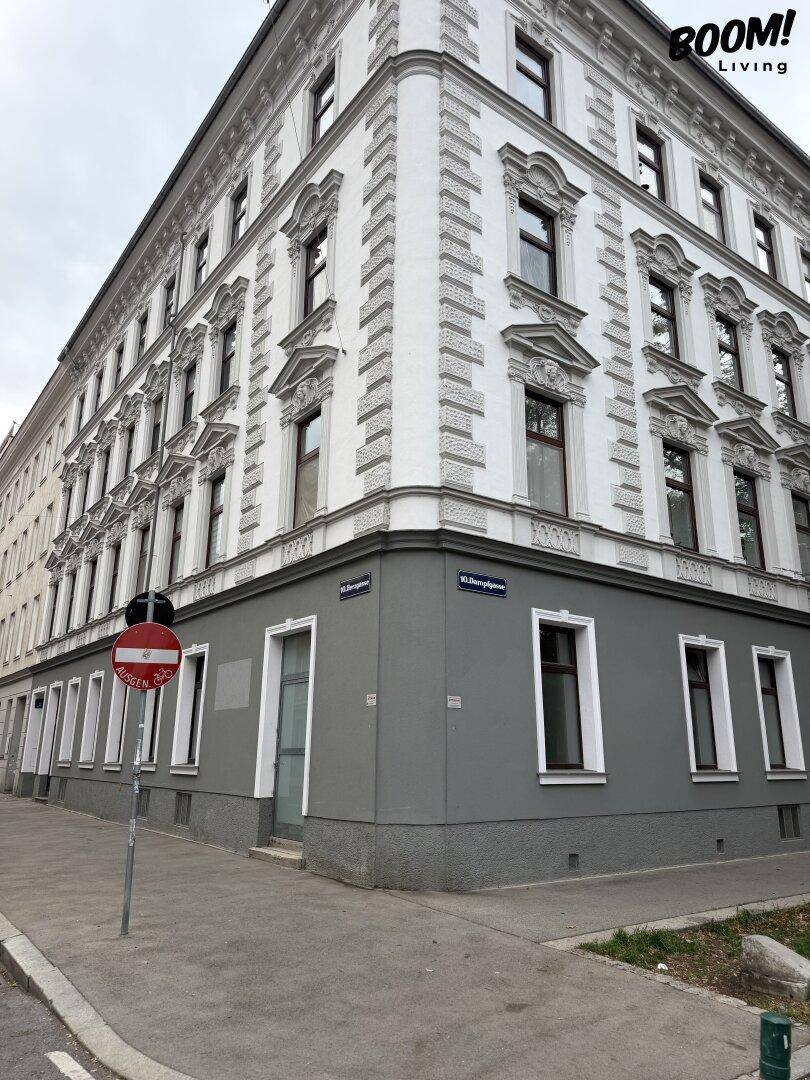 Historisches Eckgebäude mit klassischer Fassade, vielen Fenstern und einem grauen Sockelbereich.