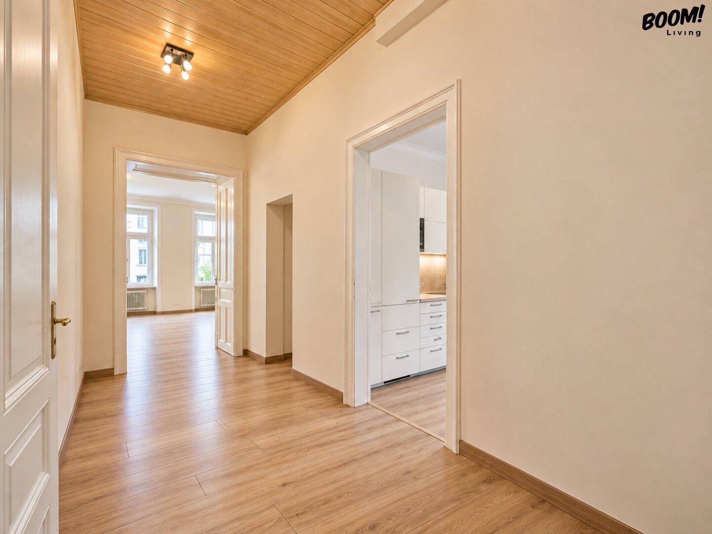 Heller Flur mit Holzboden und Holzdecke, der zu weiteren Räumen der Wohnung führt.