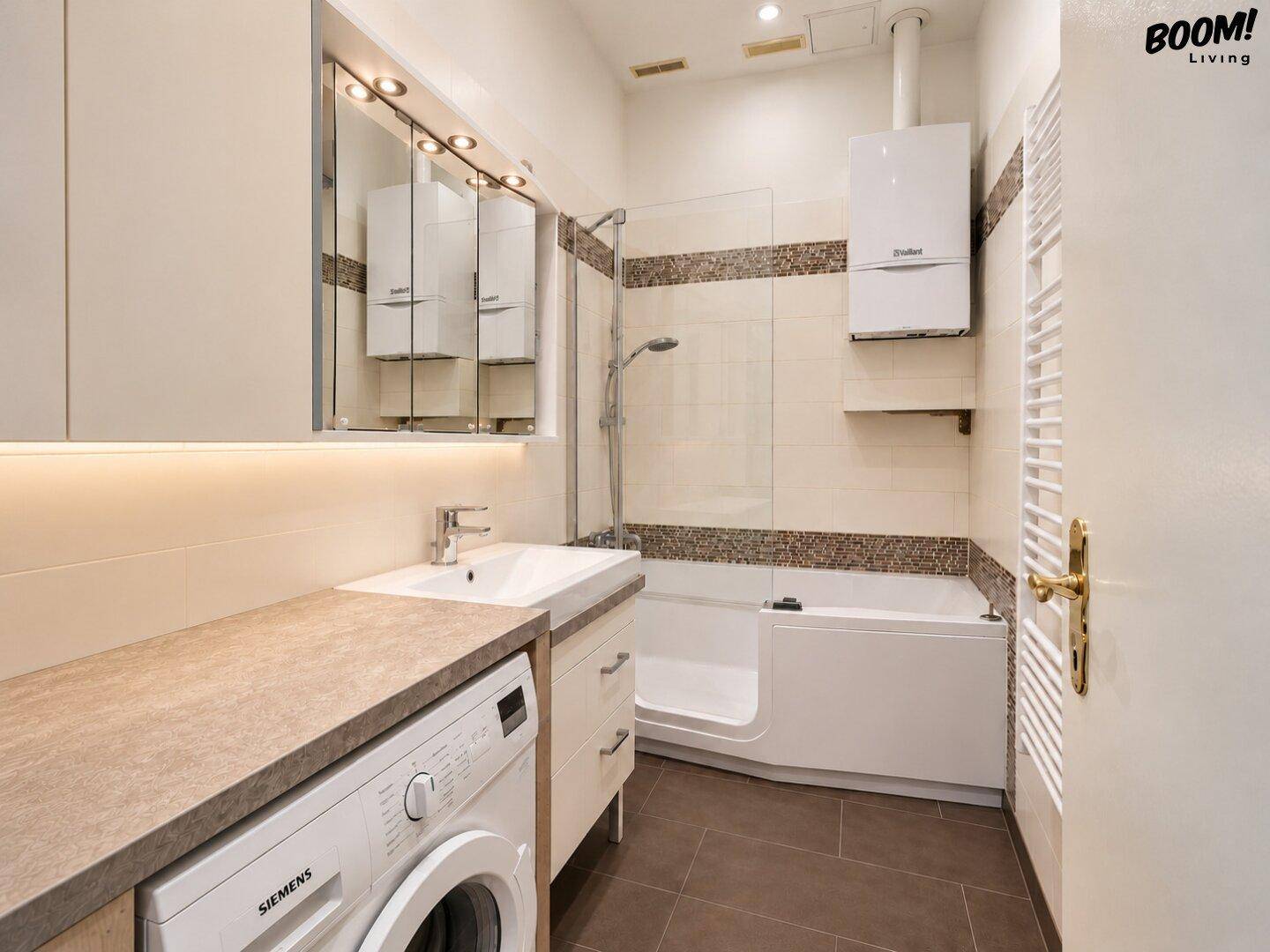 Modernes Badezimmer mit Badewanne, Dusche, Waschbecken und integrierter Waschmaschine.