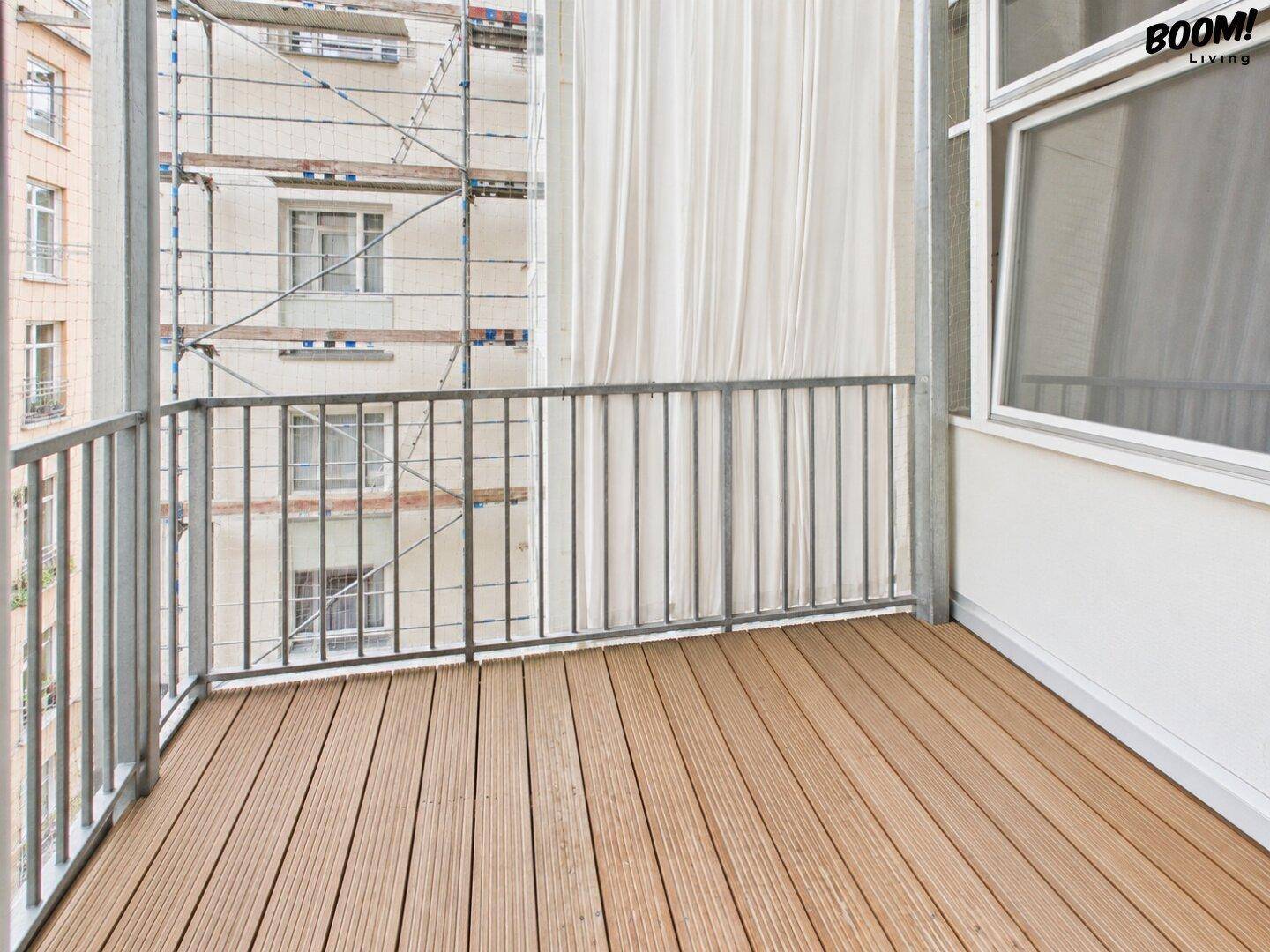 Leerer Balkon mit Holzboden und Metallgeländer, Blick auf ein Baugerüst.