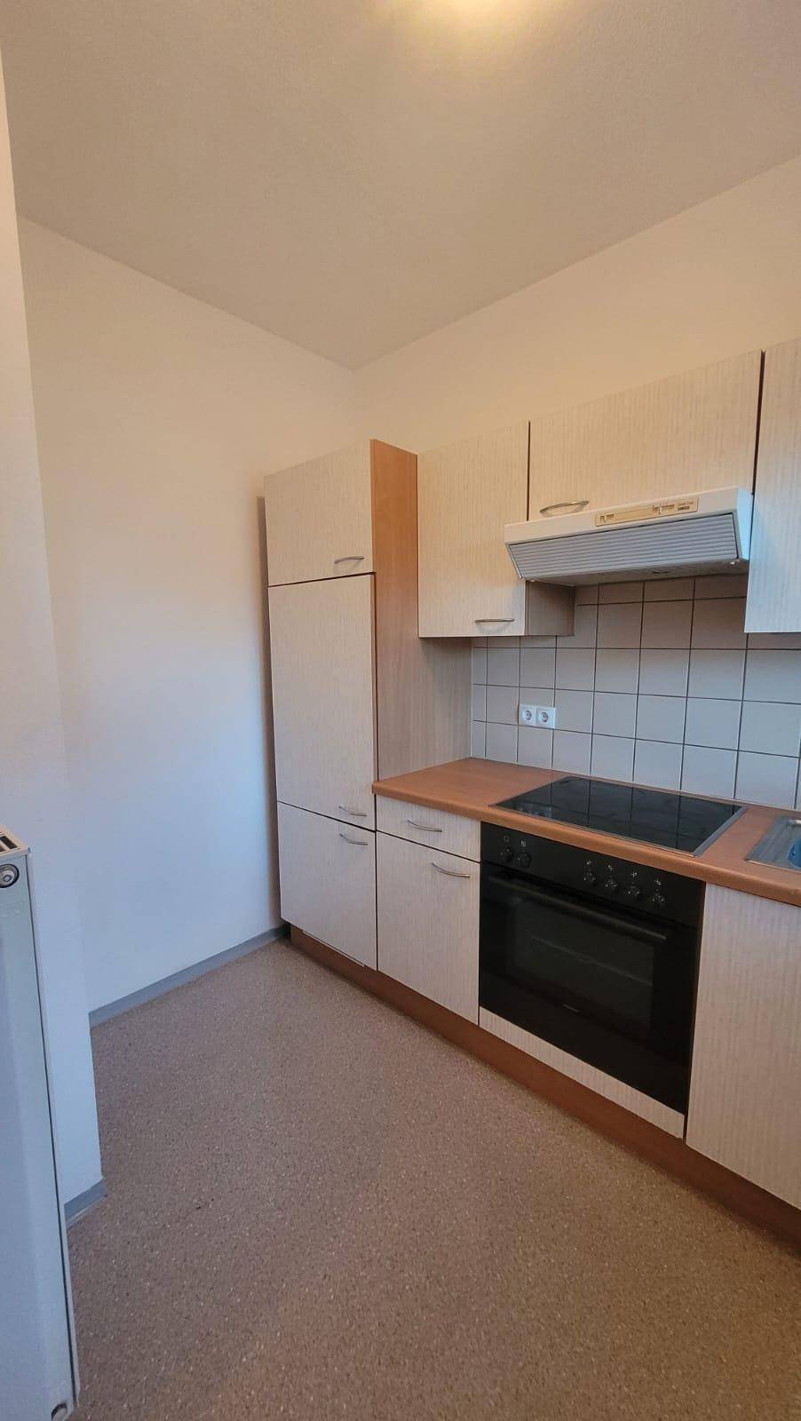 Kompakte Einbauküche mit hellen Schränken, Kochfeld und Backofen, praktisch und funktional.