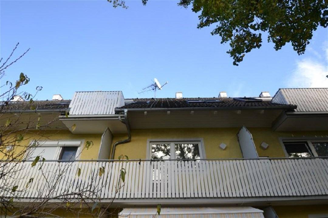 Fassade des Gebäudes mit mehreren Balkonen und Satellitenschüssel unter blauem Himmel.