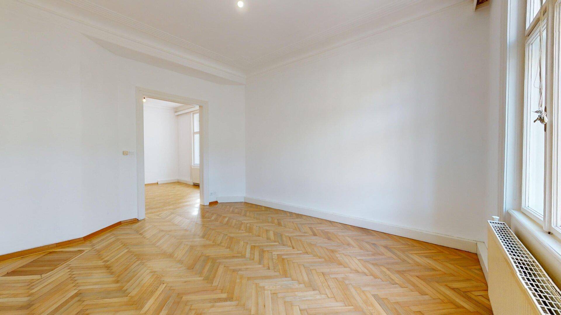 Geräumiges Zimmer mit Fischgrätparkett und weiß gestrichenen Wänden, bereit zur Gestaltung.