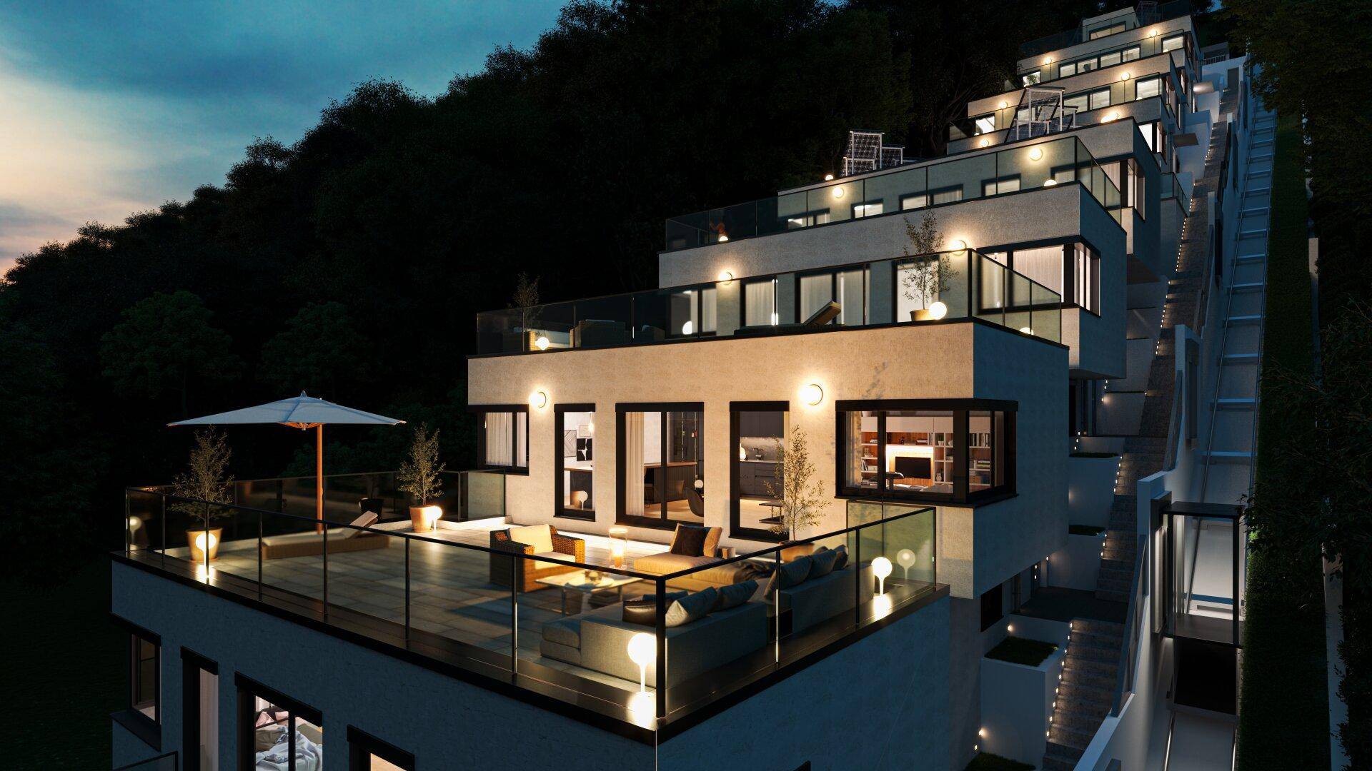 Beleuchtete Terrassenwohnanlage bei Nacht mit großzügigen Außenbereichen und moderner Architektur.
