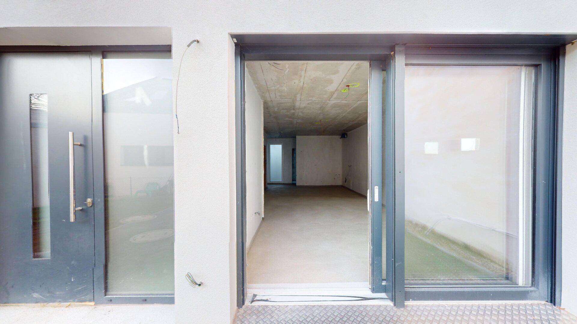 Moderne Eingangstür und große Glasschiebetür, die den Zugang zum Innenraum ermöglichen.