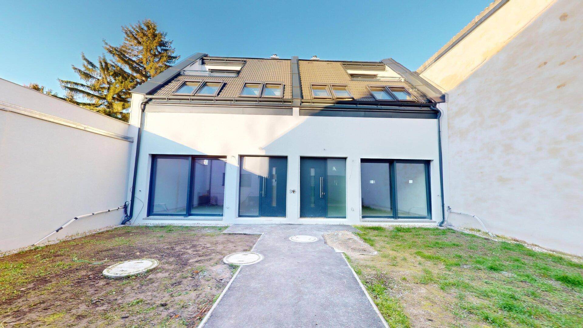 Neubau-Doppelhaushälfte mit moderner Fassade und noch unfertigem Vorgarten.