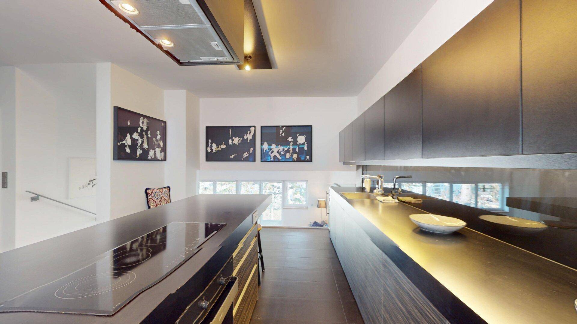 Hochmoderne Küche mit großer Kochinsel, Induktionskochfeld und eleganten dunklen Schränken.