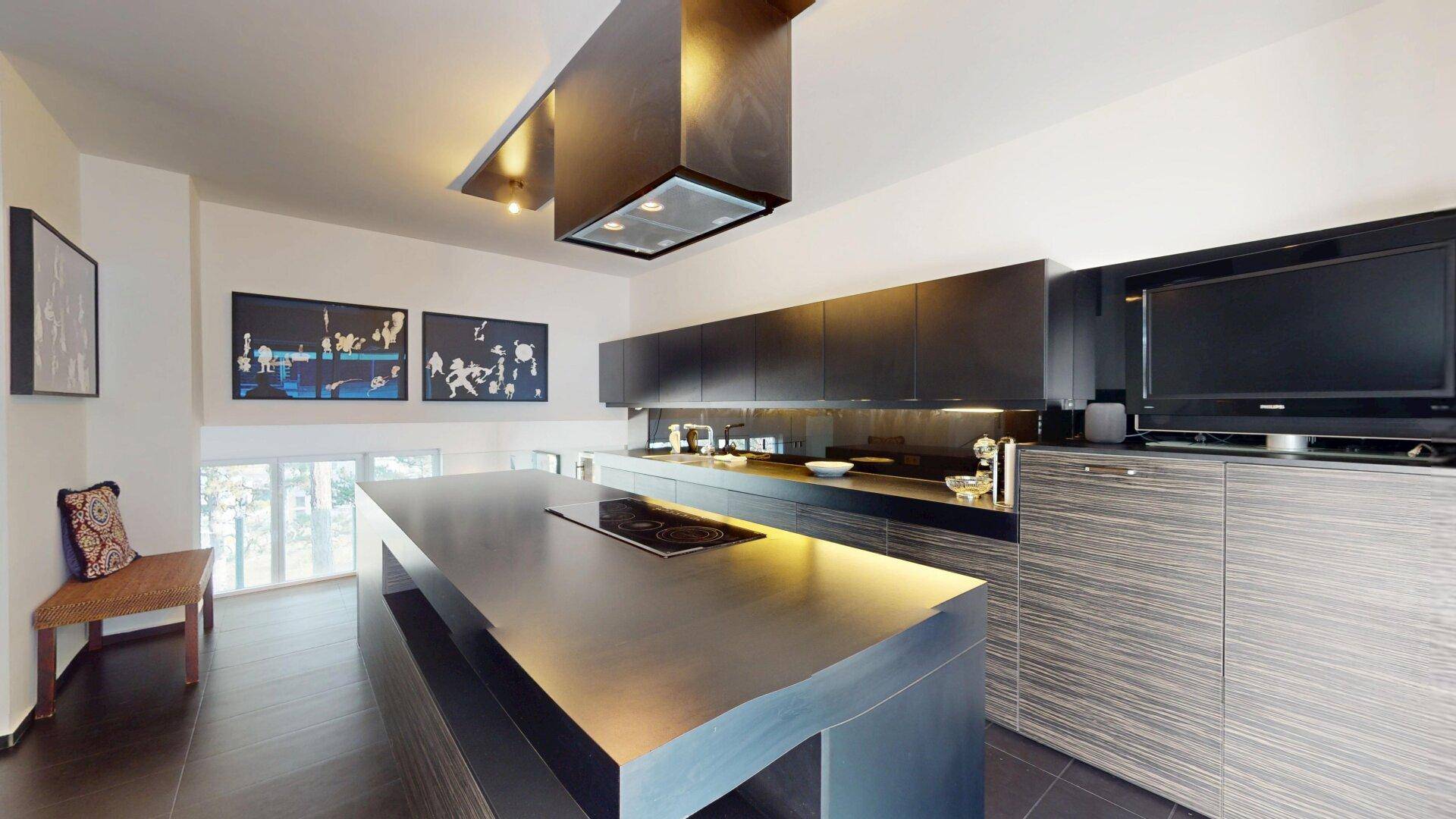 Geräumige, moderne Küche mit großer Kochinsel, Induktionskochfeld und eleganten dunklen Schränken.