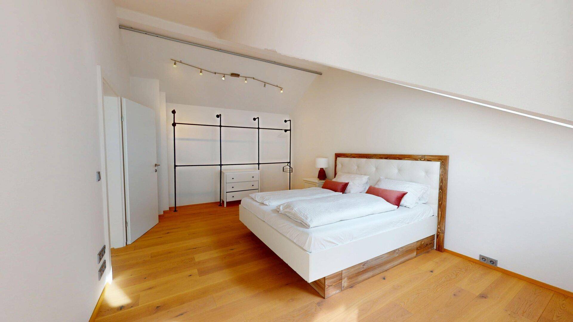 Geräumiges Schlafzimmer im Dachgeschoss mit Doppelbett und offenem Kleiderschranksystem.