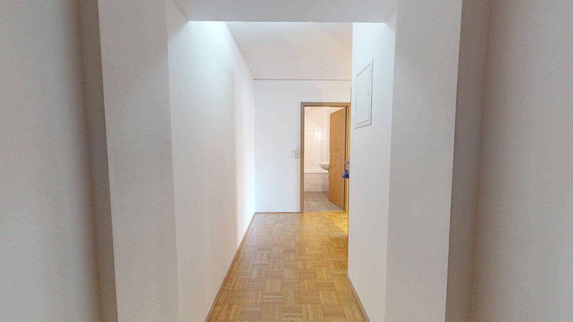 Heller Flur mit Parkettboden, der zu weiteren Räumen der Wohnung führt.
