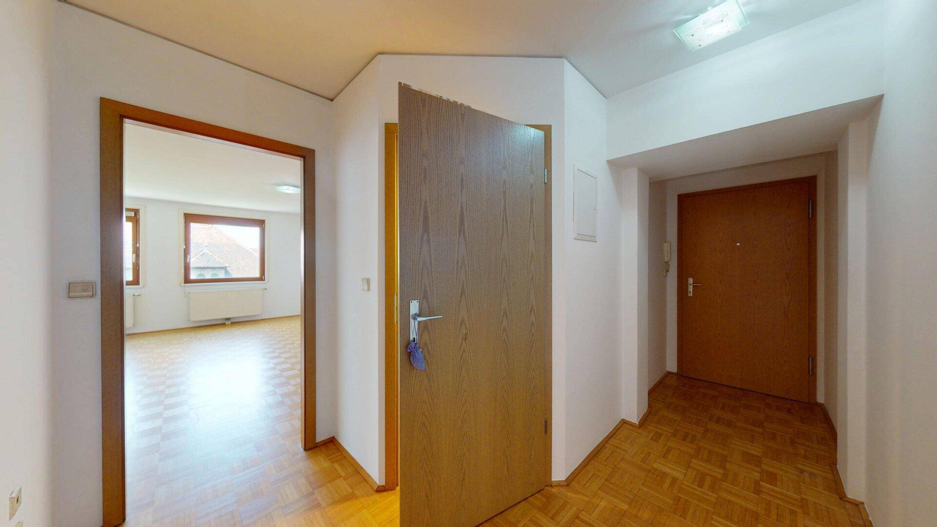 Eingangsbereich mit Parkettboden und Zugang zum Wohnzimmer und zur Haustür.