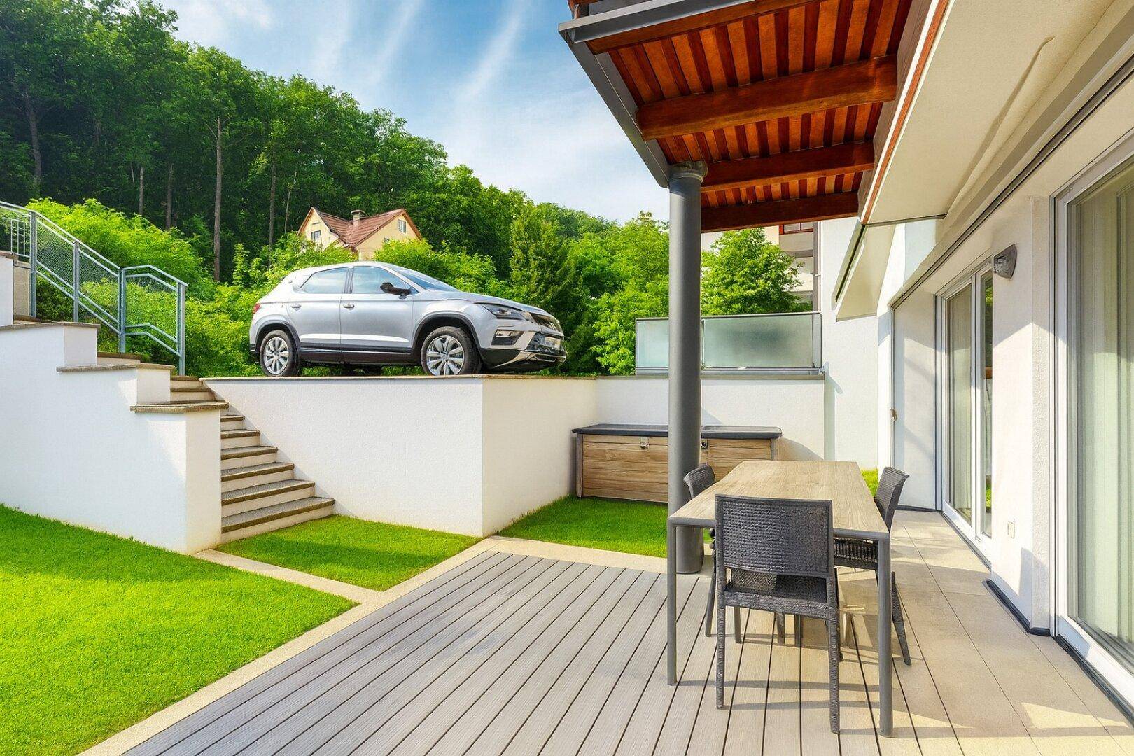 Sonniger Terrassenbereich mit Sitzgelegenheiten, Rasenfläche und Blick ins Grüne.