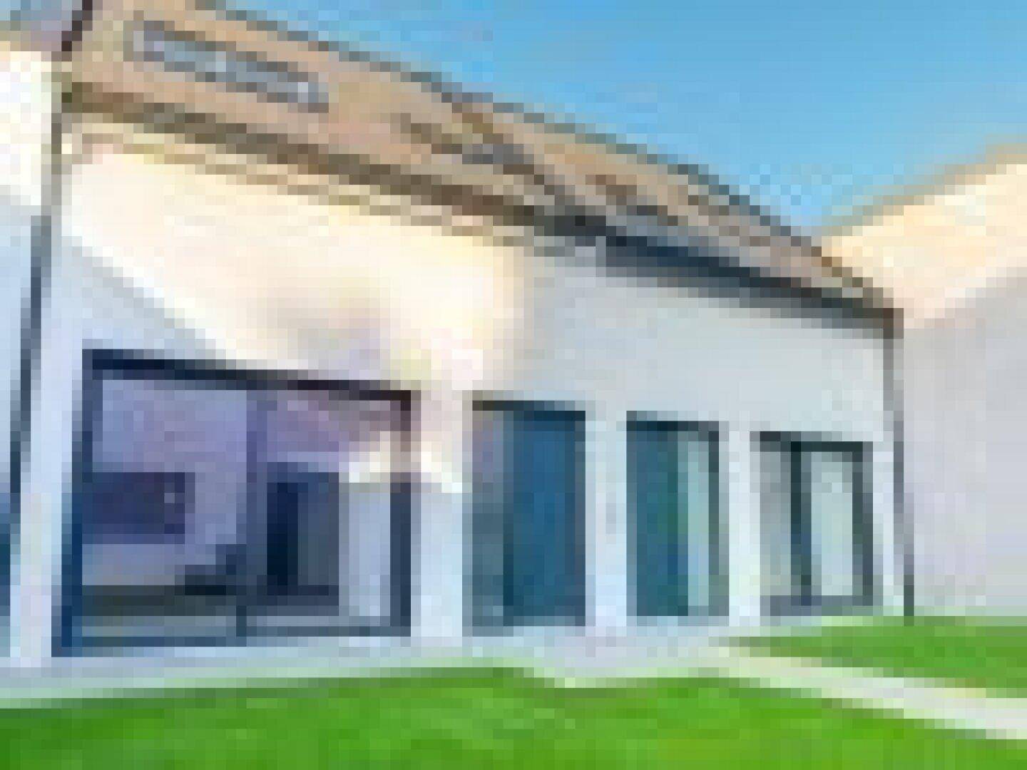 Moderne Fassade des Neubaus mit großen Glasflächen und klaren Linien.
