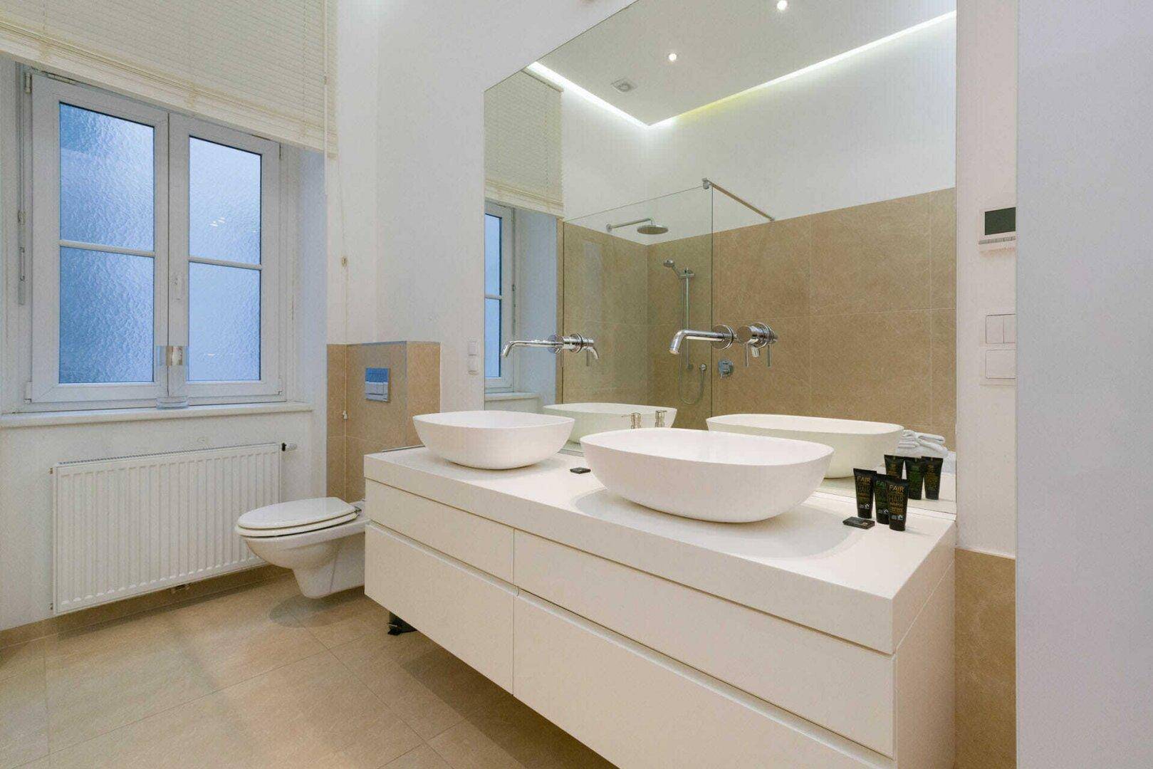 Elegantes Badezimmer mit zwei Aufsatzwaschbecken, großem Spiegel und modernen Armaturen.