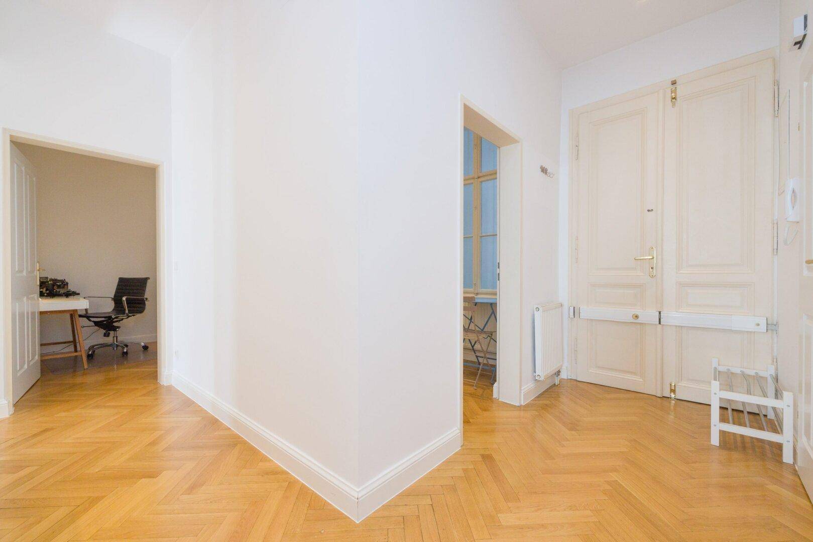 Heller Flur mit Parkettboden, der verschiedene Räume der Wohnung miteinander verbindet.