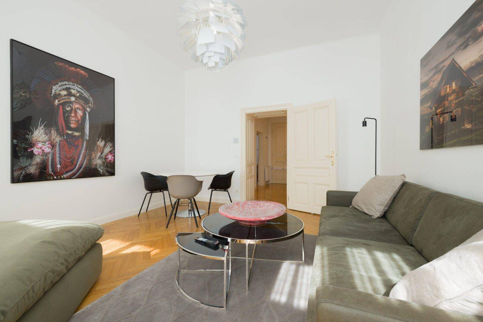 Offener Wohn- und Essbereich mit bequemer Couch, Esstisch und hellem Parkettboden.