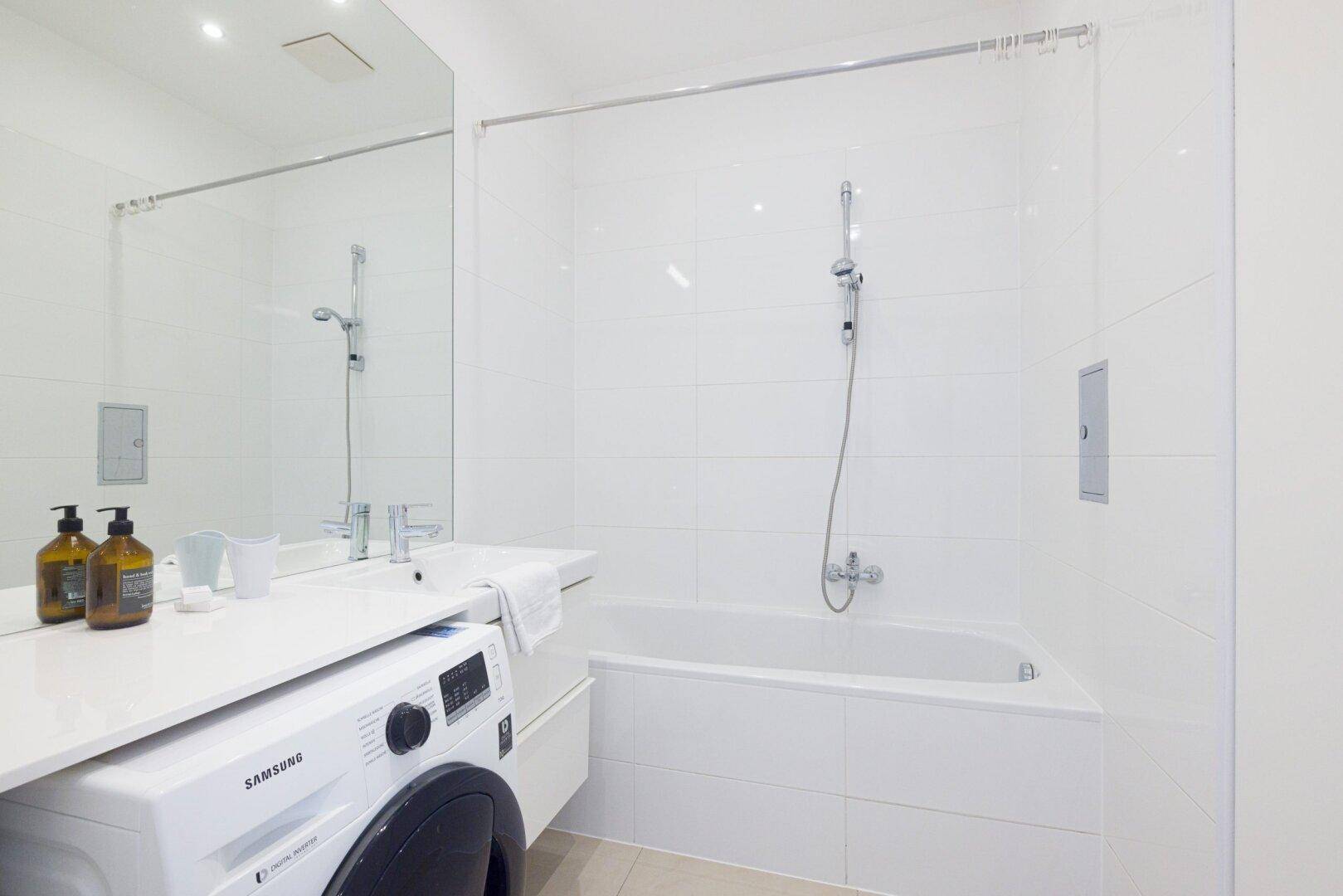 Sauberes Badezimmer mit Badewanne, Duschfunktion und weißen Fliesen an den Wänden.