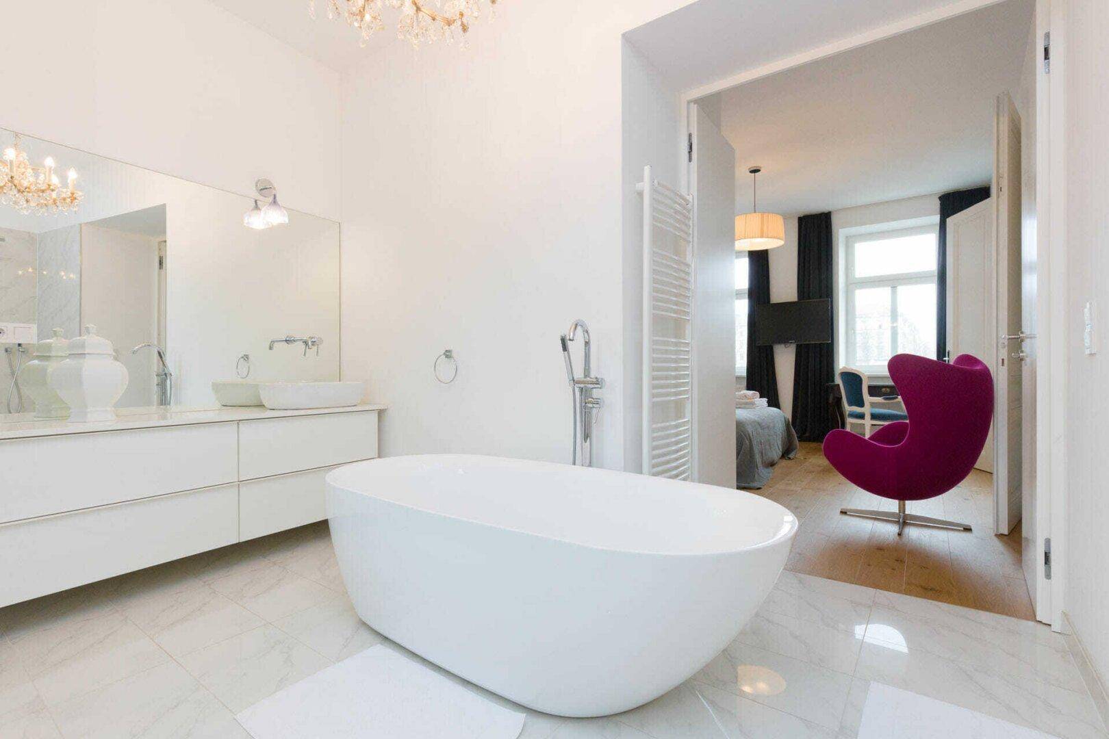 Elegantes Badezimmer mit freistehender Badewanne, Doppelwaschbecken und Zugang zum Schlafzimmer.