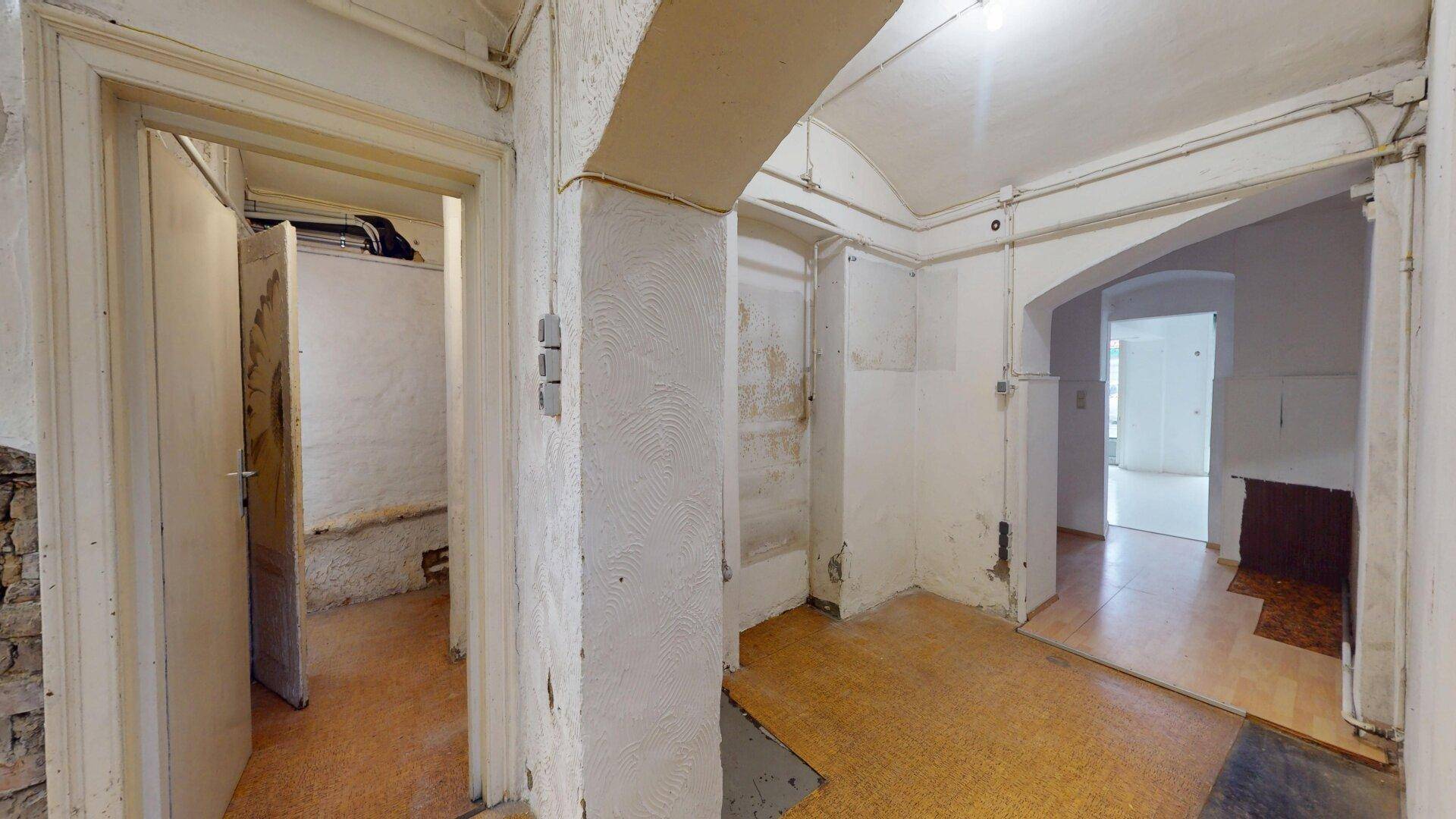 Flur im Kellerbereich mit mehreren Türen und sichtbaren Leitungen an den Wänden.