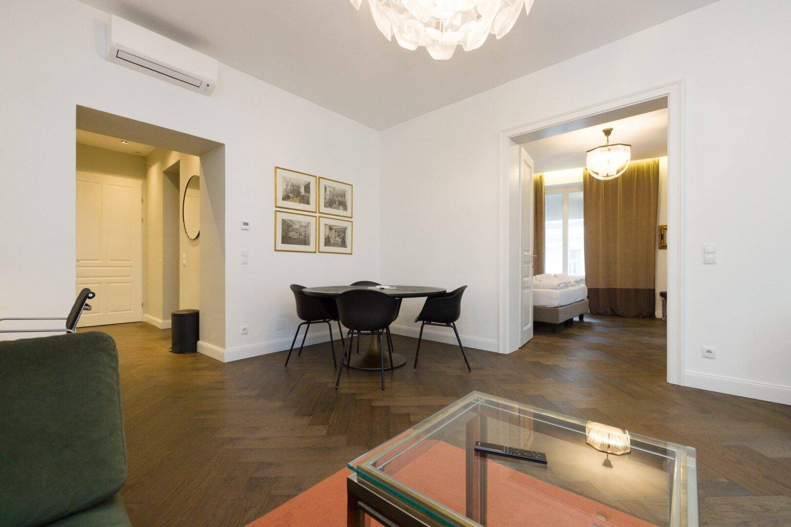 Offener Wohn-Essbereich mit modernem Esstisch und Zugang zum Schlafzimmer.