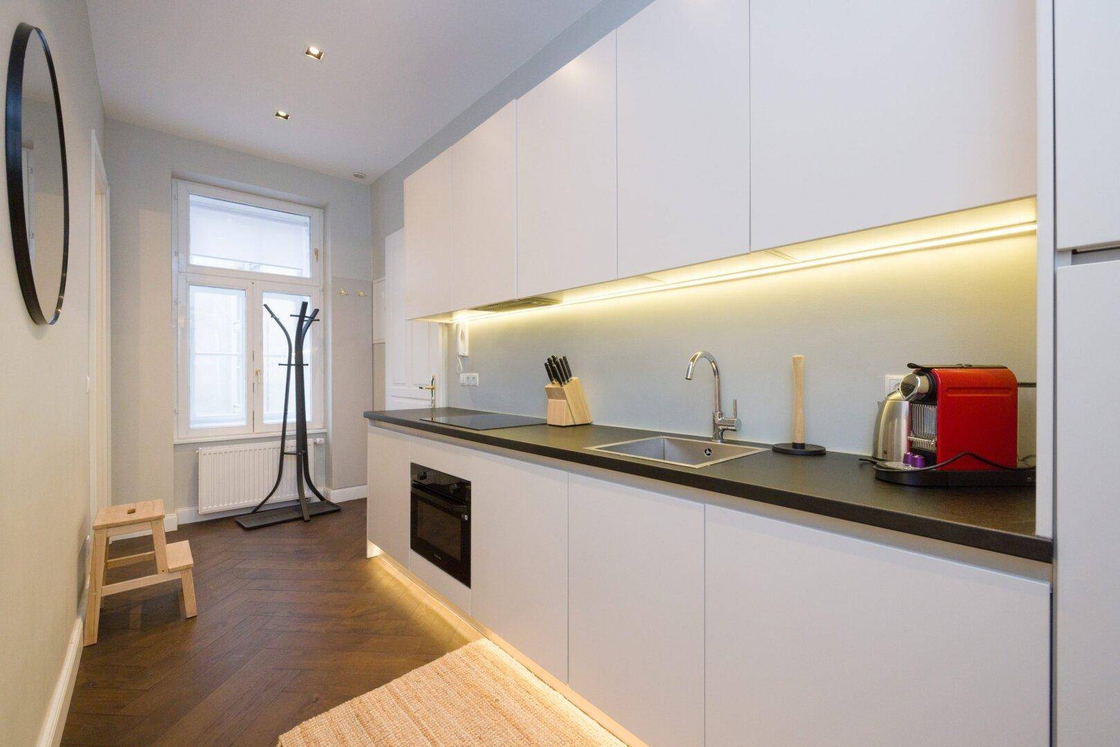 Funktionale Küchenzeile mit Fenster, Spüle und Kaffeemaschine in hellem Design.