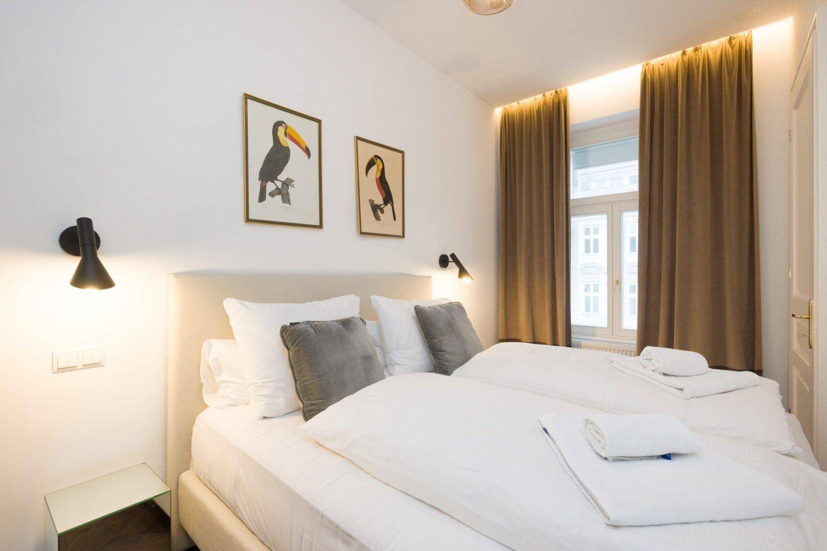 Helles Schlafzimmer mit Doppelbett, braunen Vorhängen und viel Tageslicht.