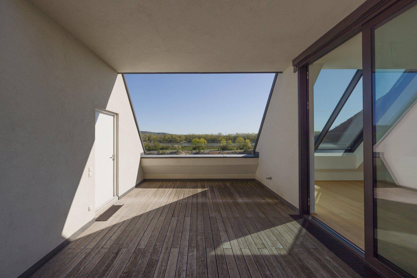Geräumiger Balkon mit Holzboden und weitem Blick über den See und die Landschaft.