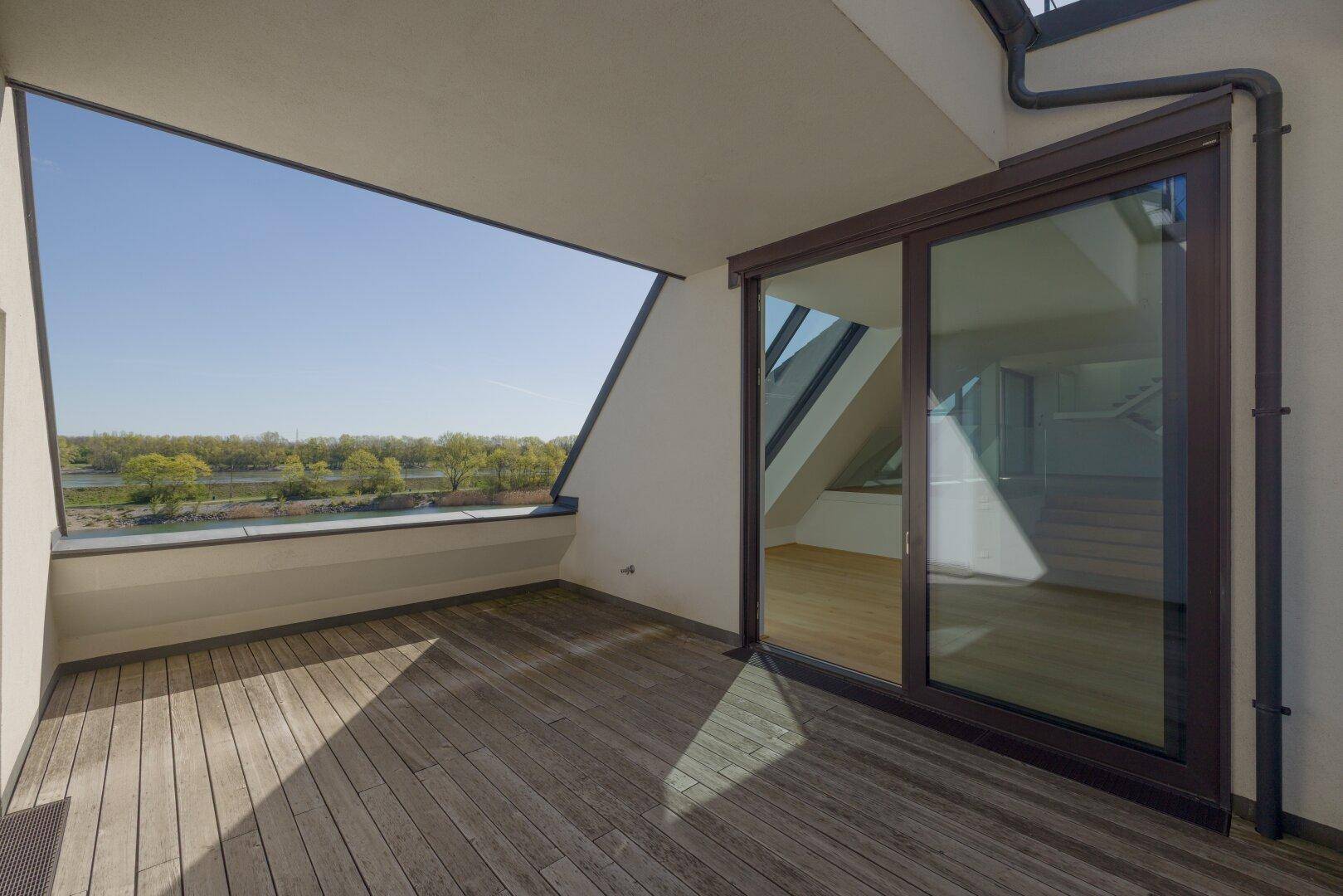 Heller Balkon mit Holzboden und Schiebetüren, die in den Innenbereich führen.