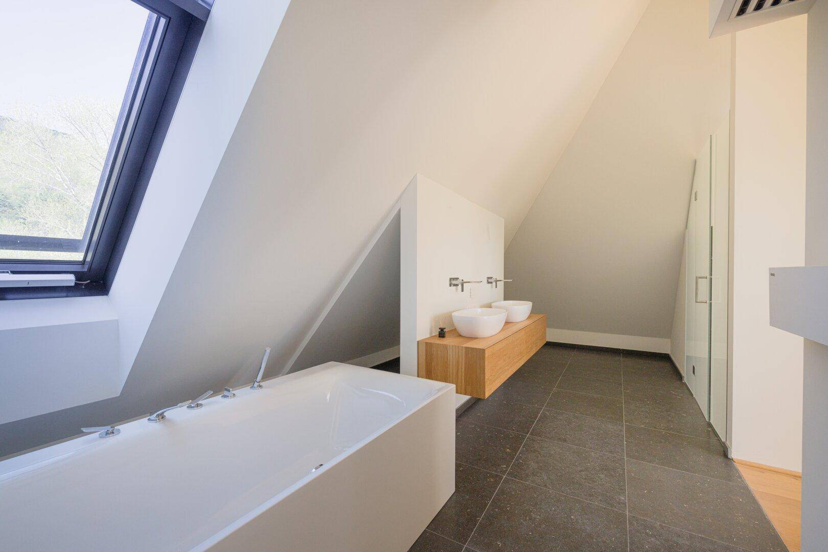 Geräumiges Badezimmer im Dachgeschoss mit Badewanne, Doppelwaschbecken und Dachfenster.