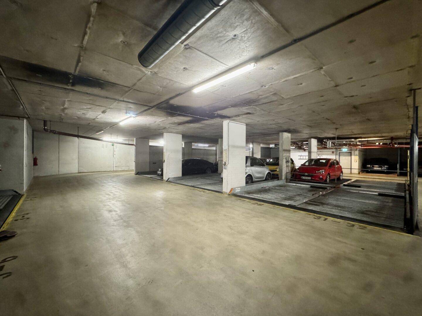 Weiterer Blick in die Tiefgarage mit zahlreichen Parkplätzen und modernen Parkliftsystemen.