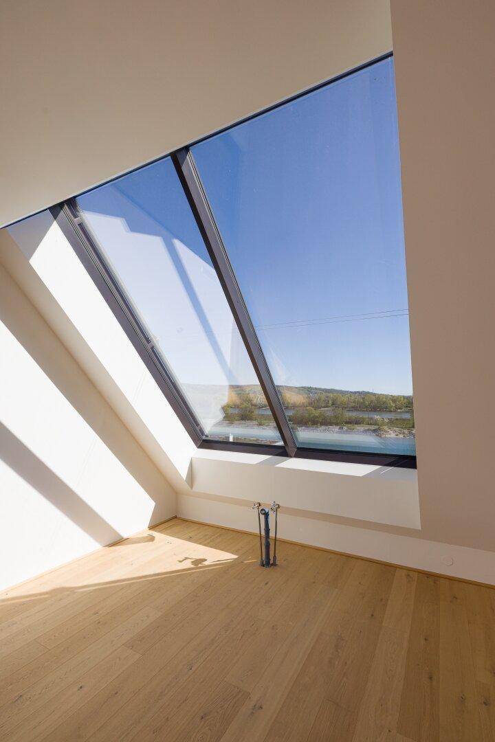 Heller Raum mit Holzboden und großem Dachfenster, das viel natürliches Licht hereinlässt.