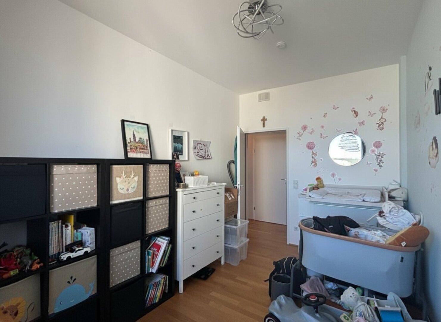 Helles Kinderzimmer mit Wickeltisch, Babybett und Stauraum.