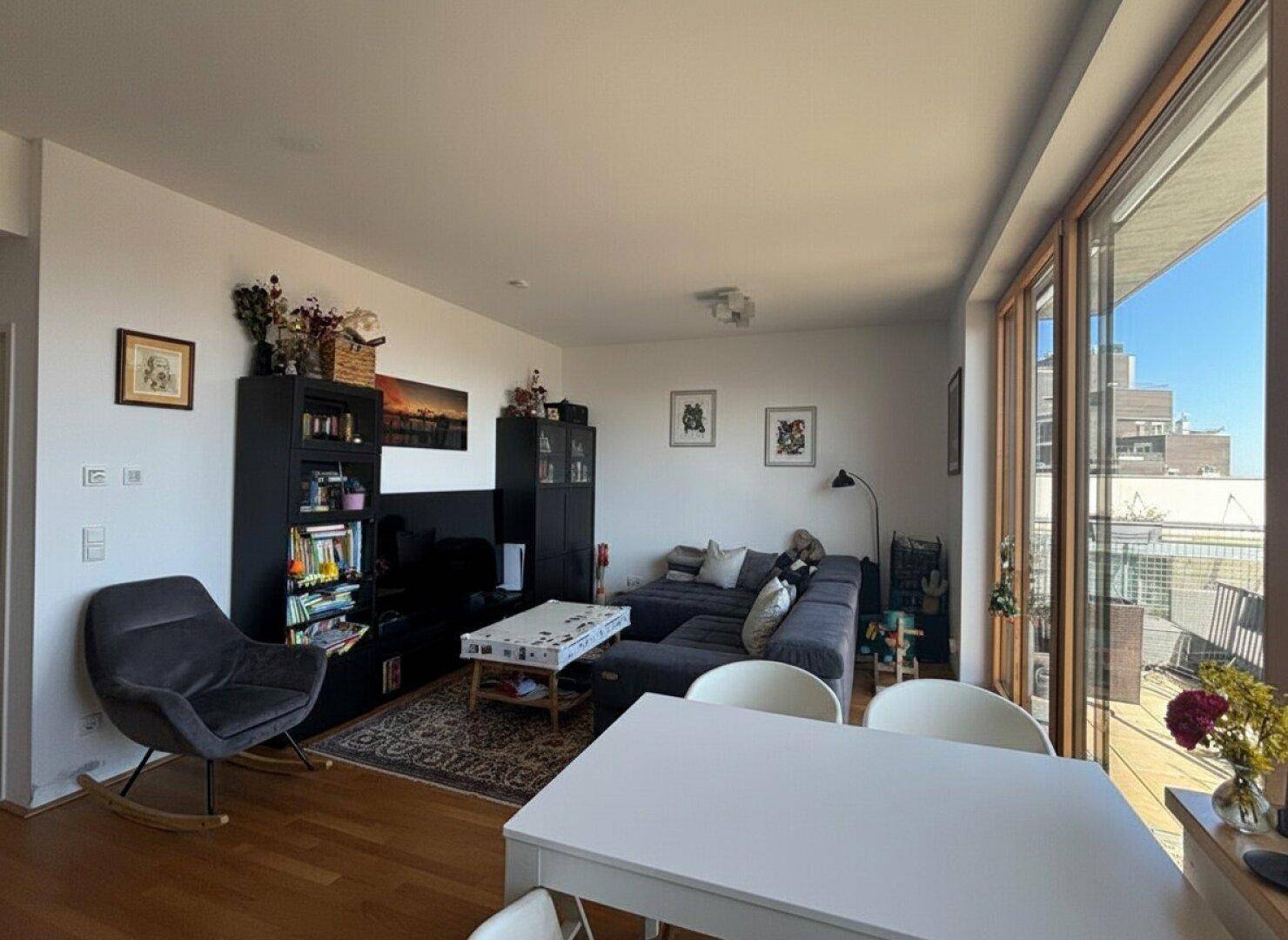 Heller Wohn- und Essbereich mit Holzboden und Zugang zu einem sonnigen Balkon.