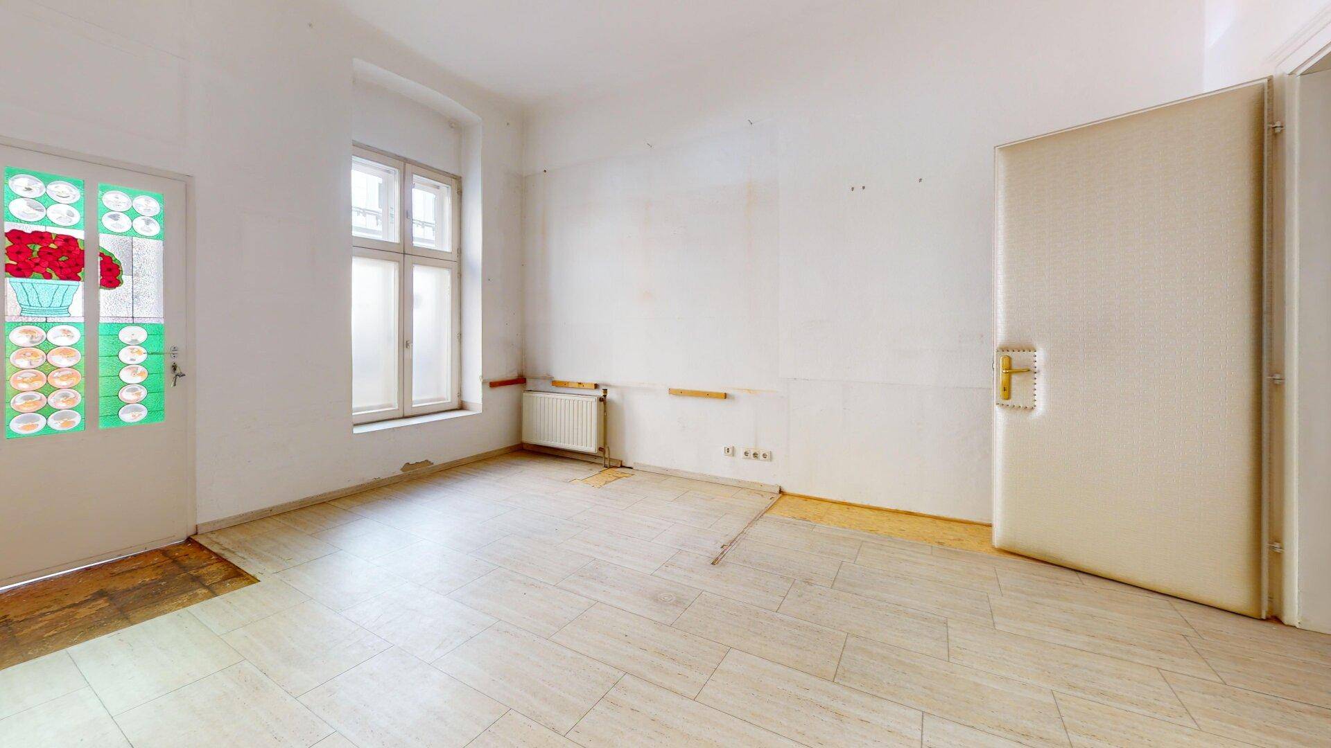 Heller Raum mit Fliesenboden und einer farbenfrohen Eingangstür, die den Raum belebt.