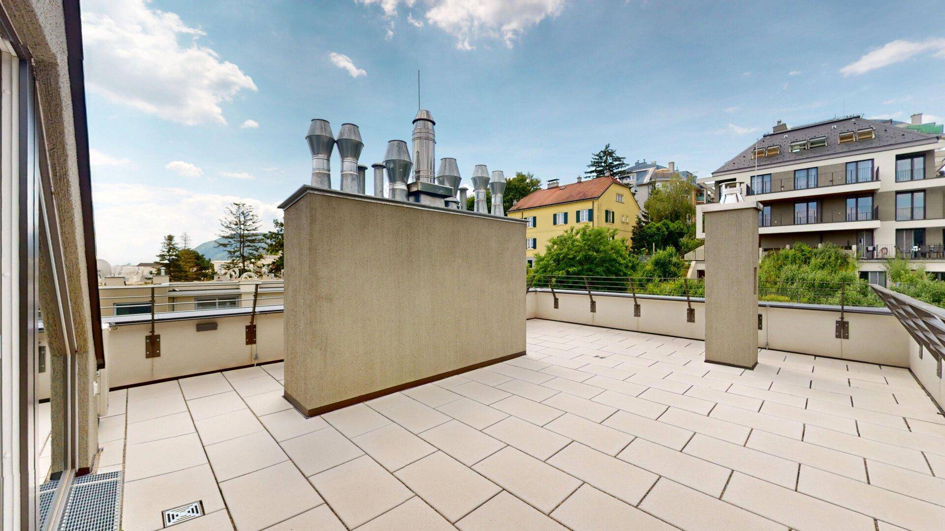 Weitläufige Dachterrasse mit Fliesenboden und Panoramablick über die Stadt und die Umgebung.