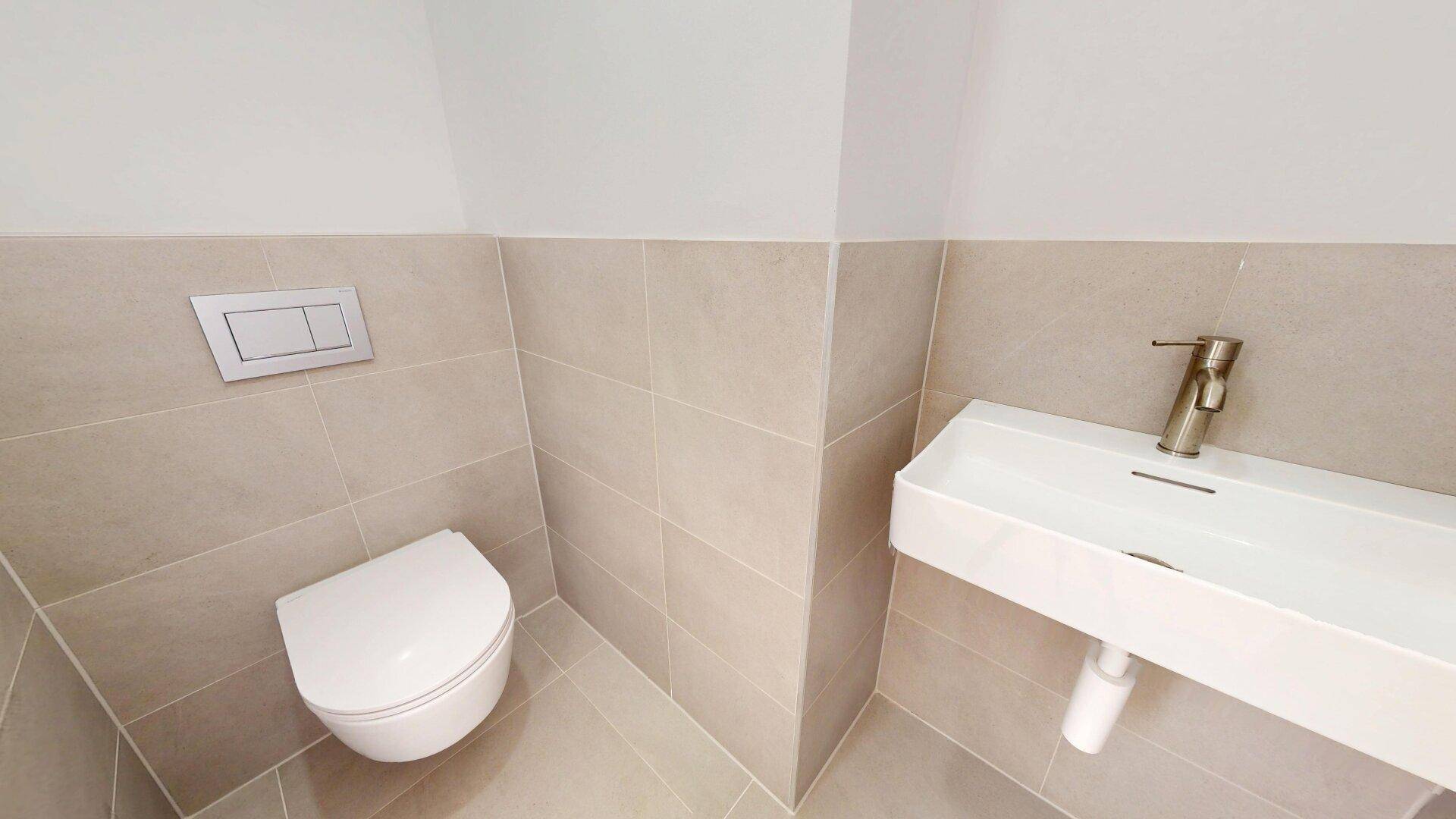 Modernes Gäste-WC mit Wand-WC und kleinem Waschtisch, gefliest in hellen Farbtönen.