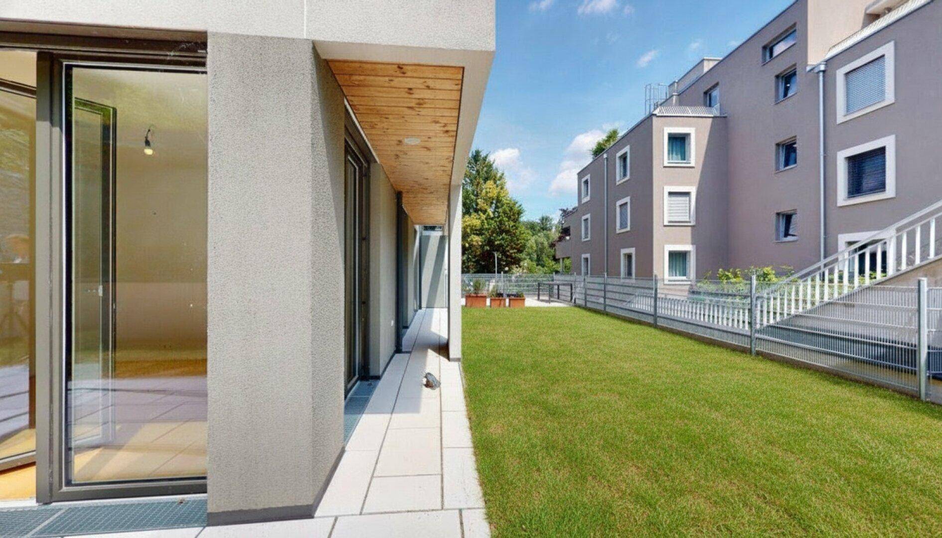 Moderne Wohnanlage mit gepflegter Rasenfläche und Außenbereich unter blauem Himmel.