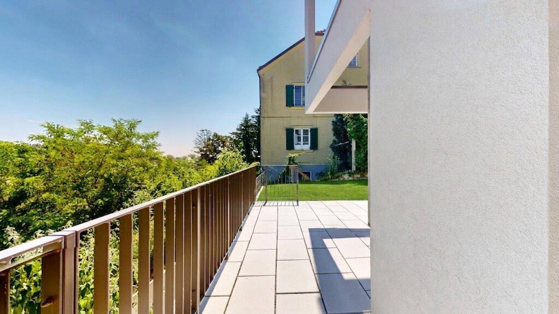 Weitläufige Terrasse mit modernem Geländer und sonnigem Ausblick auf die Umgebung.