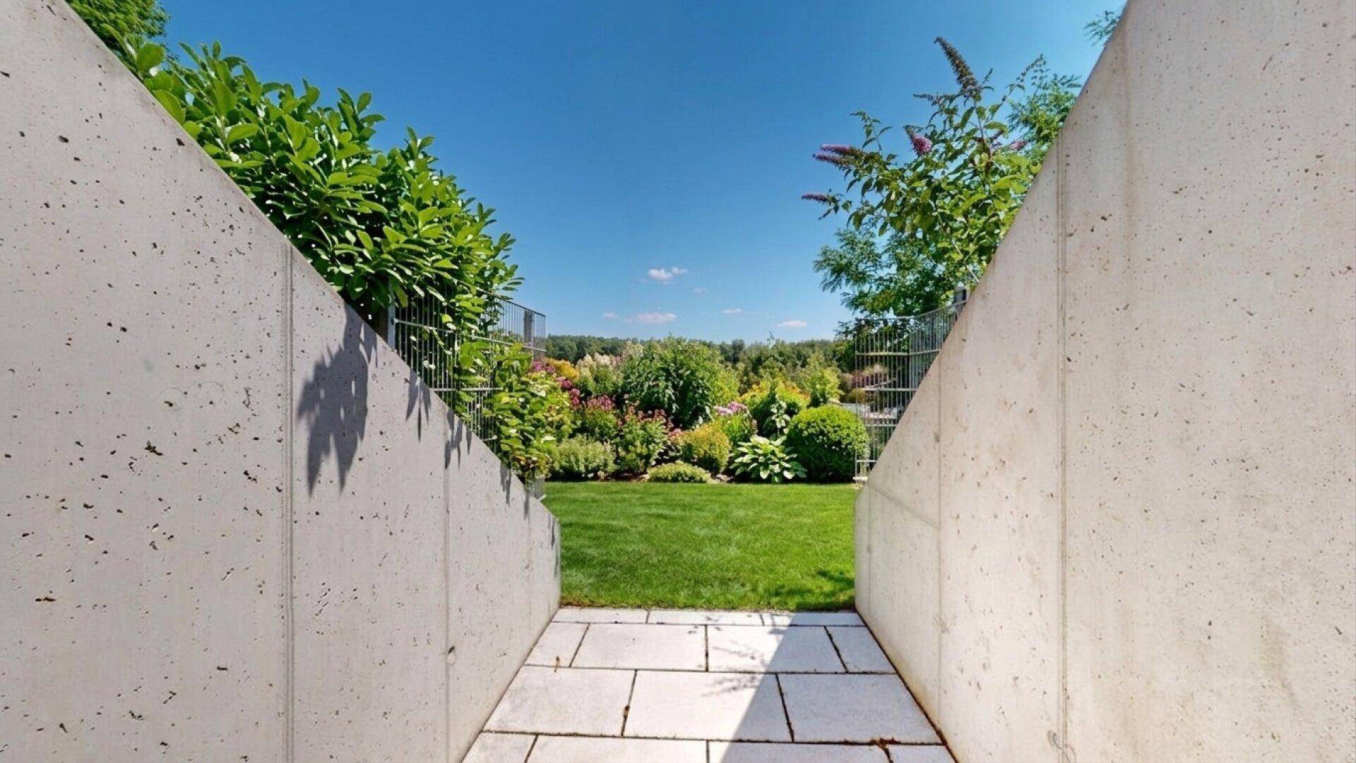Zugang zu einem gepflegten Gartenbereich mit üppiger Bepflanzung und Rasen.